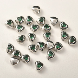 Dettagli macro di perline a cuore in argento con zircone verde per gioielli fai da te