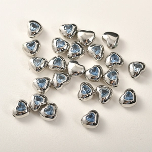Vista macro di perline a cuore in argento con zircone blu per gioielli fai-da-te