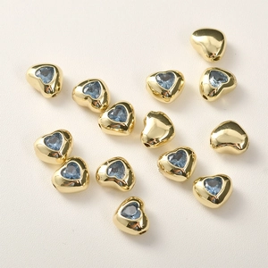 Vista macro di perline a cuore placcate oro 14k con zircone azzurro per gioielli fai da te
