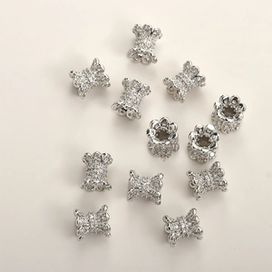 Close-up of 14k gold plated cylinder and bow-knot beads with clear zircon stones