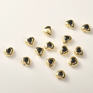 Dettaglio macro di perle distanziatrici a cuore placcate oro 14k con zircone nero