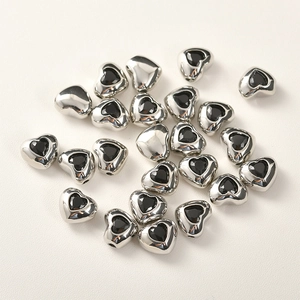 Dettaglio macro di perle a cuore argentate con zircone nero per creazione gioielli