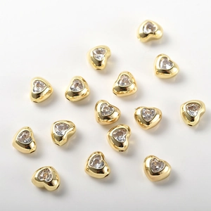 Dettaglio di perline a forma di cuore placcate oro con zirconi per creazioni fai-da-te