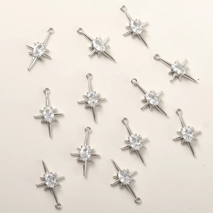 Macro shot of 11 silver starburst pendants with clear cubic zirconia for DIY jewelry
