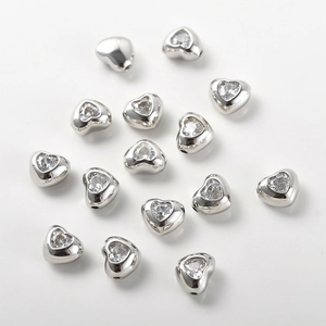 Dettaglio macro di perline a cuore in argento con zirconi per creazione gioielli DIY