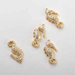 Detail van vier vergulde zeepaardje hangers met witte zirkoonstenen voor DIY sieraden maken