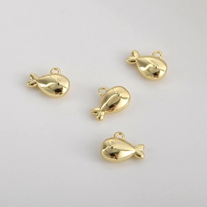 Détail de quatre breloques poissons en or poli pour la création de bijoux DIY