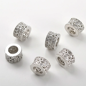Detail of 14k gold plated cylinder spacer beads with hollow flower pattern and zircons