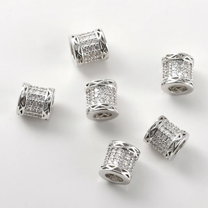 Macro detail of 14k gold-plated cylinder beads with pavé zircon and hollow pattern