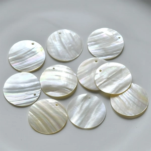 Macro detail of natural mother of pearl round charms with pre-drilled holes for jewelry DIY