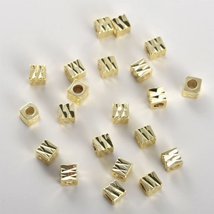 Macro-opname van 14k vergulde kubusvormige kralen met diamantgeslepen textuur voor sieraden