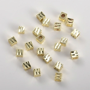 Macro-opname van 14k vergulde vierkante smile-kralen met diamantgeslepen geometrische textuur