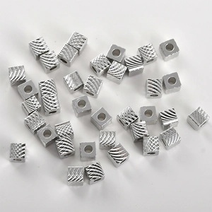Macro-detail van kubusvormige zilveren kralen met diagonale texturen voor het maken van sieraden