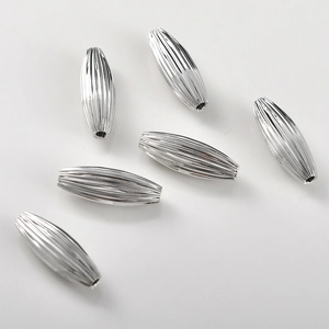 Macro detail of silver spindle shaped beads with fine vertical ridges for DIY jewelry