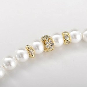 Macro detail of 14k gold-plated heart floral spacers and zircon beads on pearl jewelry