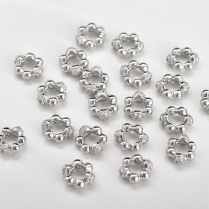 Macro view of flower-shaped spacer beads with cubic zirconia inlays for DIY jewelry