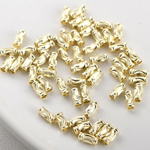 Macro shot of 14k gold plated brass curved tube spacer beads with textured wave pattern