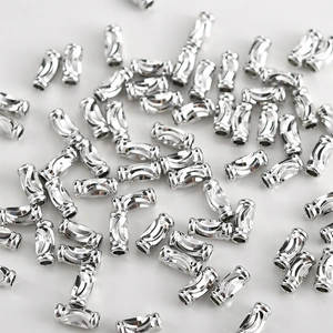 Macro shot of silver curved tube beads with wave texture for DIY jewelry making