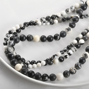 Macro view of spotted natural stone round beads with marble textures in a white dish