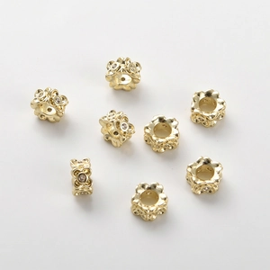 Macro view of 14k gold plated four-leaf flower beads with micro-set zircon stones
