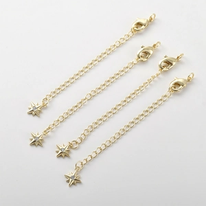 Dettaglio di catene extender placcate oro 14k con pendenti a stella e chiusure a moschettone