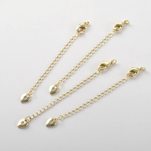 Dettaglio di cinque catene di estensione placcate oro 14k con moschettoni e ciondoli a cuore