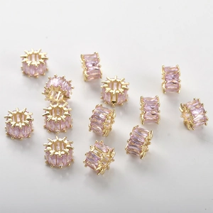 Detailed macro view of 14k gold-plated cylinder spacer beads with pink zircon inlay