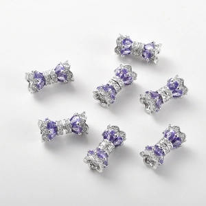 Detail of 14k gold plated bow-shaped connectors with purple and clear zircon stones