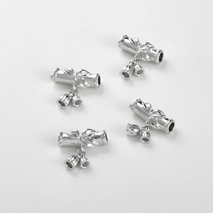 Macro view of 4 silver-plated lily of the valley tube beads with relief texture