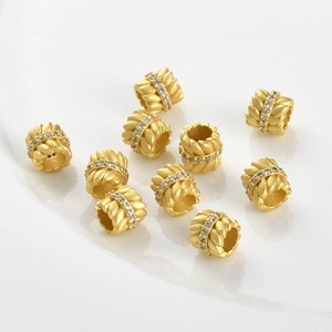 Gros plan de perles d'espacement dorées avec texture en spirale et zircons blancs