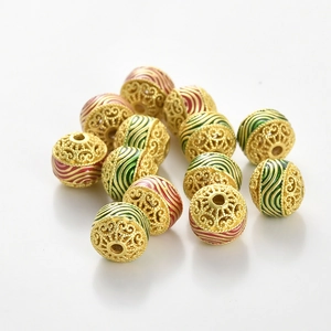 Détail de perles en cuivre plaqué or avec émail rouge et vert pour la création de bijoux