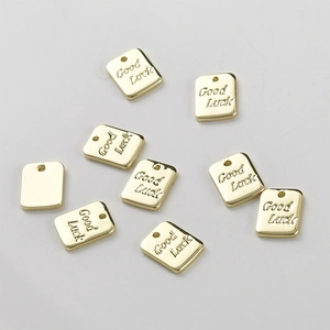 Close-up of gold-plated rectangular metal tags with Good Luck engraving for DIY jewelry