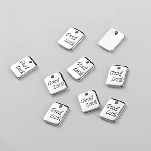 Macro detail of silver-plated rectangular pendants with Good Luck engraving for DIY