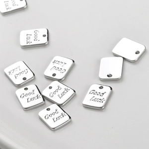 Detailed view of silver stainless steel rectangular tags with Good Luck engraving