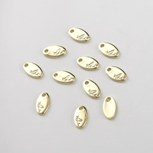 Detailed view of oval 14k gold plated charms with engraved letters for DIY jewelry
