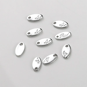 Macro shot of silver plated oval metal charms with flower engraving and signature details
