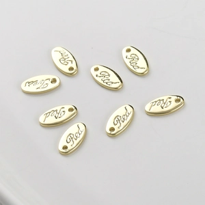 Macro shot of oval 14k gold-plated metal charms with Red engraving for DIY jewelry making
