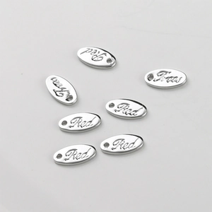Close-up of polished silver oval pendants with engraved floral text and pre-drilled holes
