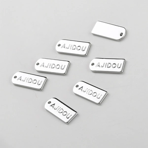 Macro view of rectangular silver metal tags with AJIDOU engraving and hanging holes