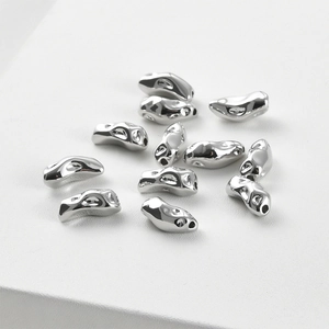 Vue macro de perles en métal liquide argenté irrégulier pour bijoux DIY avec trous