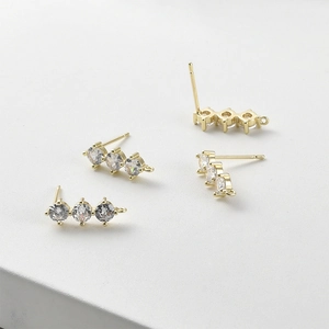 Dettaglio di orecchini a perno placcati oro 14k con tre zirconi e anelli per creazione gioielli