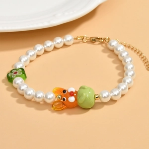 Dettaglio della perla di vetro a coniglio e fiore verde su un bracciale di perle finte