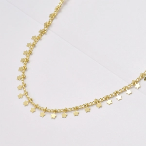 Vue macro de breloques étoiles dorées sur une fine chaîne d'extension pour bijoux DIY