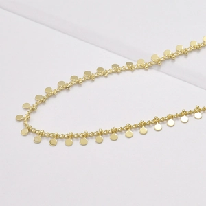 Détail macro d'une chaîne torsadée plaquée or 14 carats avec petits pendentifs ronds DIY