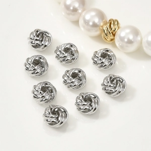 Neuf perles nœud en spirale argentées pour création de bijoux sur fond blanc