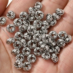 Gros plan de perles de nœuds tressés argentés pour bijoux DIY sur une main