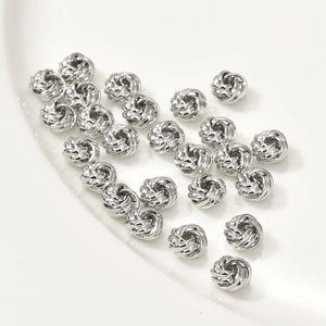 Vue macro de perles à nœuds argentés pour bijoux DIY sur une assiette en céramique