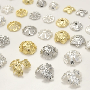 Dettaglio di vari copriperla dorati e argentati in design a fiore per gioielli fai da te