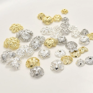 Dettaglio macro di copriperla e distanziatori in oro 14k e argento per gioielli fai da te