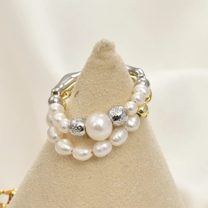 Detail of layered gold-plated textured ring with pearls on a suede display stand